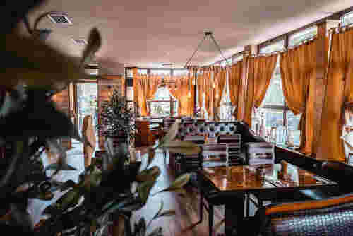 Delphi Restaurantinnenraum mit Holzmöbeln und orangenen Vorhängen