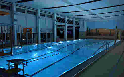 Schwimmhalle Aquarena abends mit beleuchtetem Pool