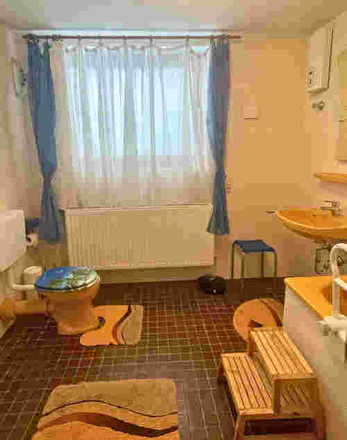 Badezimmer mit orangener Garnitur und blauen Vorhängen Badezimmer mit orangener Garnitur und blauen Vorhängen